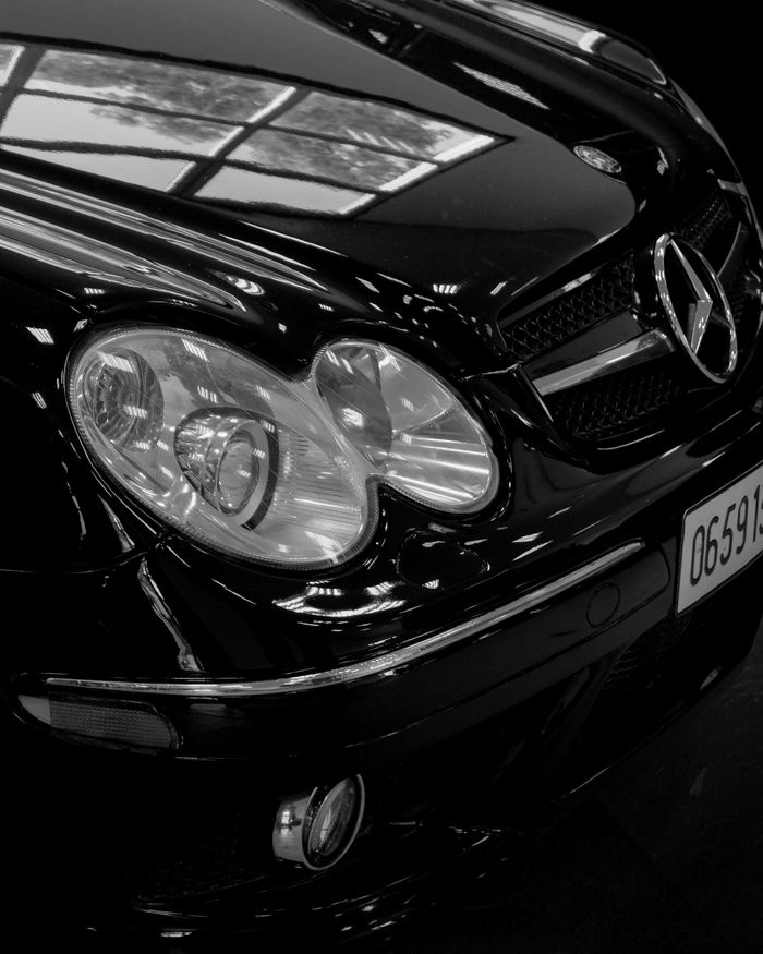 who-we-are Elegant black Mercedes Benz with shining headlights, close-up shot highlighting luxury and design.